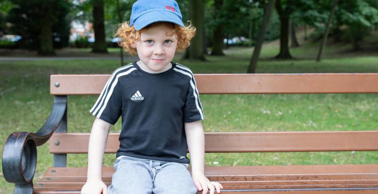 A young boy at a community event, sitting on a bench