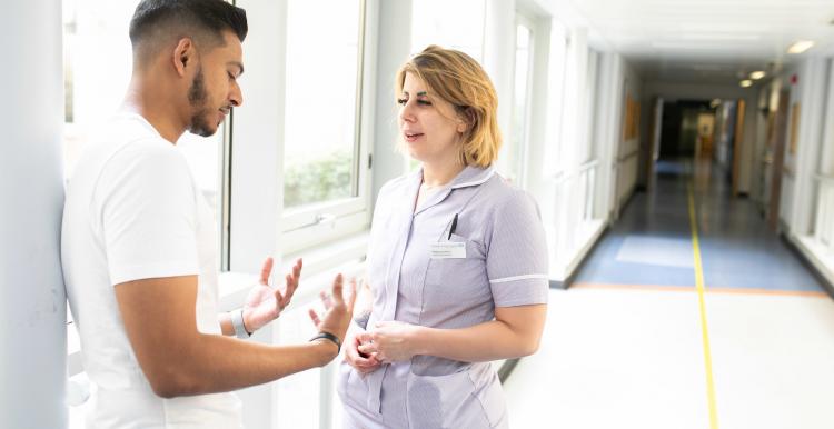 Two people speaking in a corridor