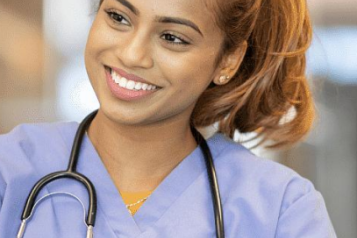 A female health professional in blue scrubs smiling