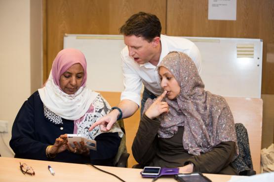 Two women and a man looking at a mobile phone