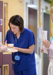 Three women in a hallway filling out a form. Two are clinicians.