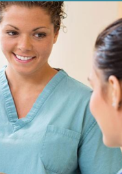 A woman in scrubs smiling to another woman